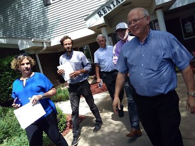 Five adults walk toward the camera as they exit a building.