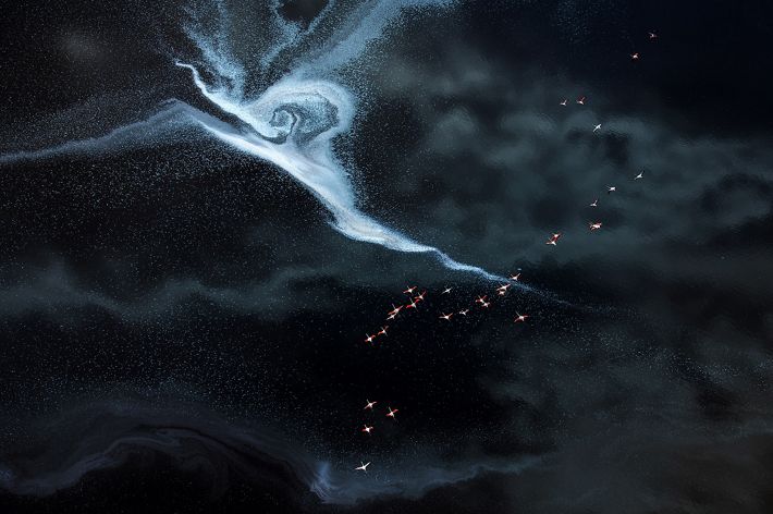 A flock of flamingos fly over the colorful salt lake, the floating foam pattern looks like lightning on the lake.