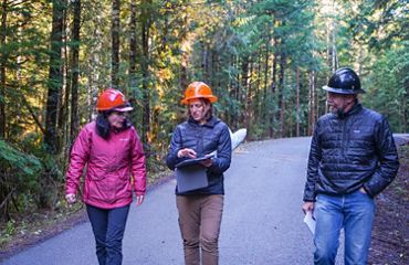 A group of three scientists walking through a forest.
