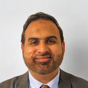 A man wearing a suit poses for a headshot.