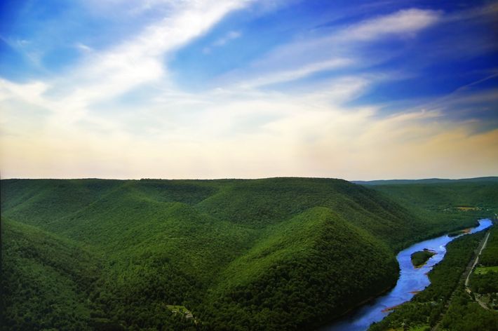 A strong and wide river flows through green trees.