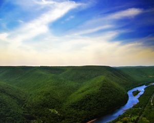 Aerial view of a river flowing through tree-covered mountains.