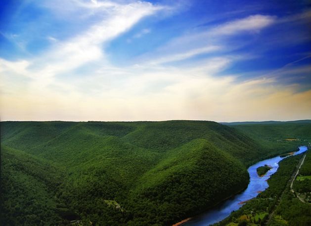 A river flows into the horizon cutting through lush green mountains.