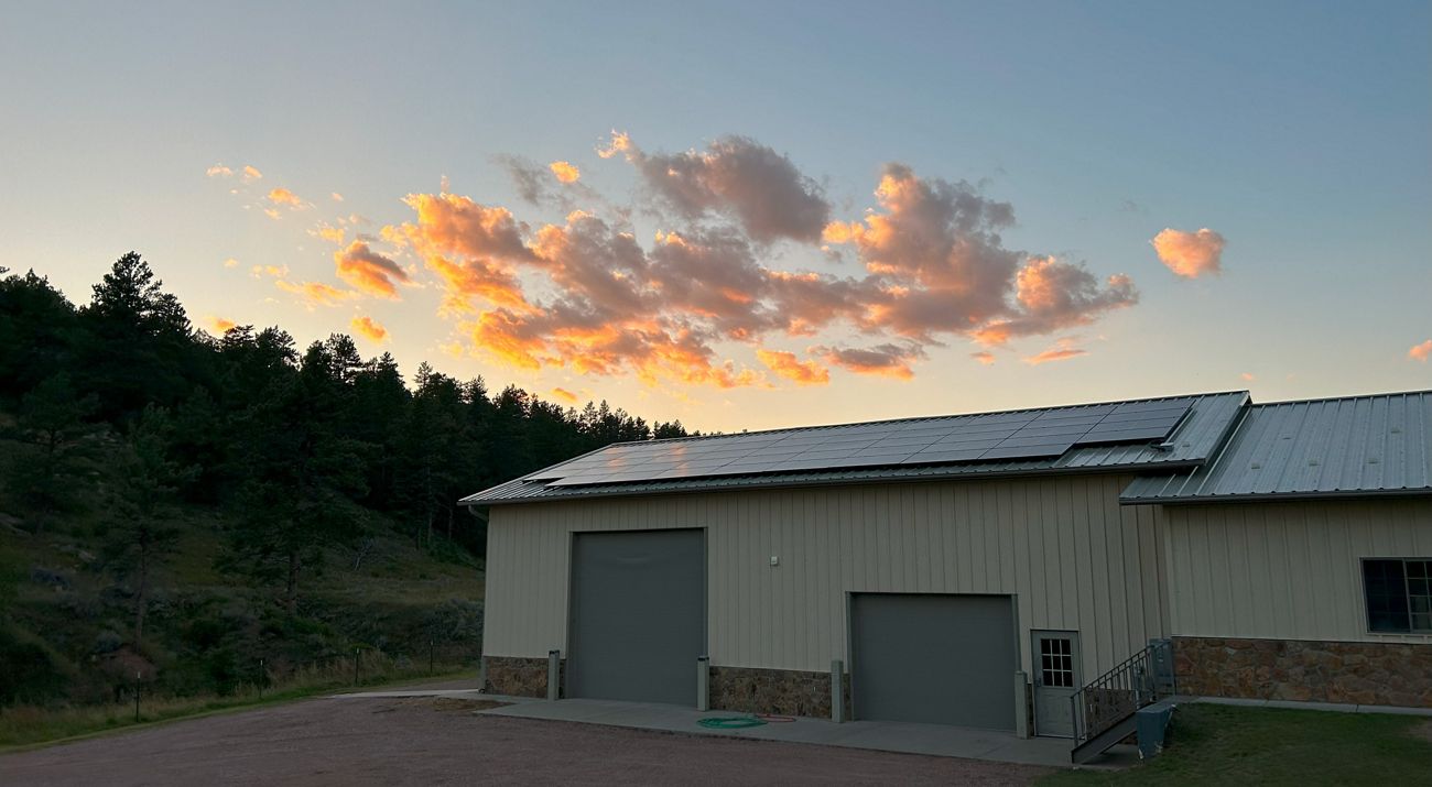 Sunset over a building with solar panels on the roof.