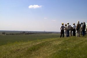 A group of people standing on a grassy hill overlooking the farm fields that will be restored at Emiquon.