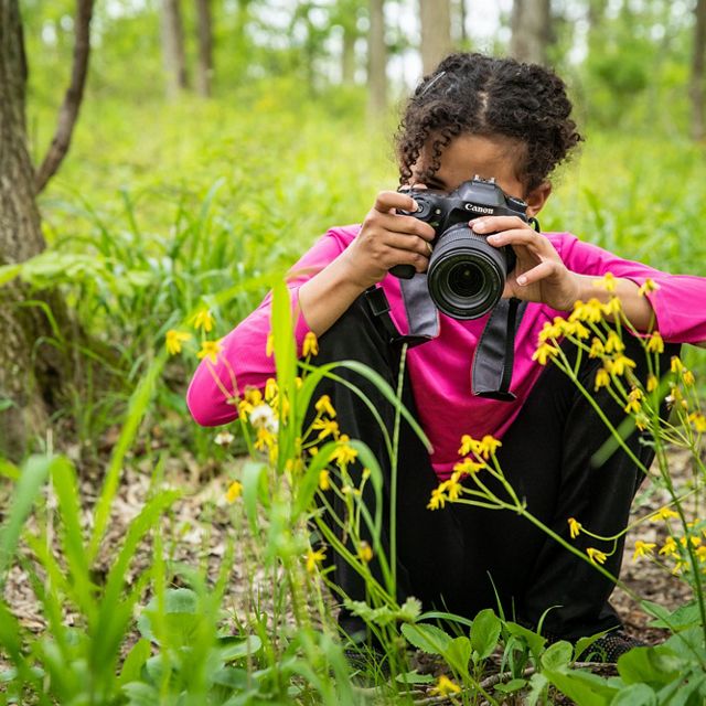 A girl photographs wildflowers.