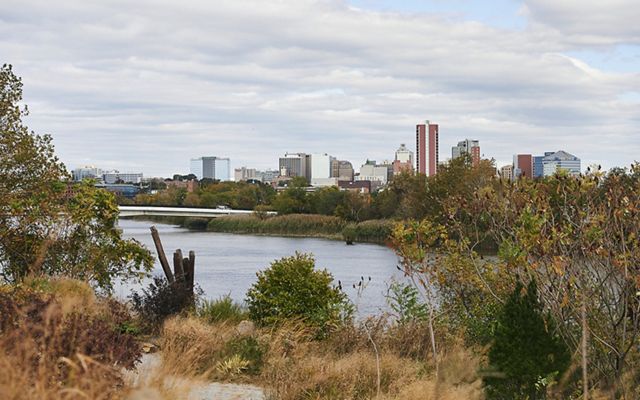 View of Wilmington, Delaware's city skyline across the Brandywine River. Tall buildings stretch up towards the low clouds.