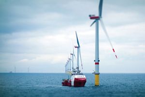 Wind farm towers with transfer vessel in the ocean.