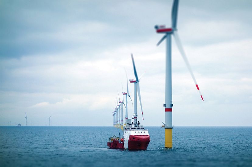 Wind farm towers with transfer vessel in the ocean.