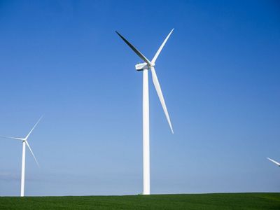 Three large wind turbines against a bright blue sky.