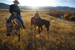 Two ranchers on horseback near sunset on an Idaho ranch.