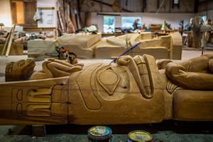 A wooden totem pole on a carving table.