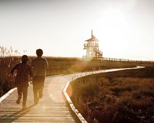 Two children running on a boardwalk in the sunshine at the Great Salt Lake Shorelands preserve in Utah.