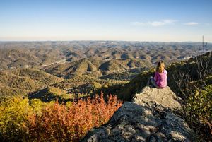 A person sits on a rock that provides a view of a vast landscape.