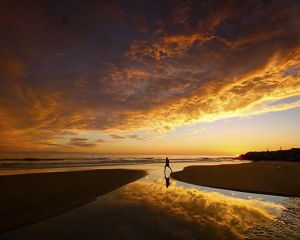 Person running on the beach at sunset.