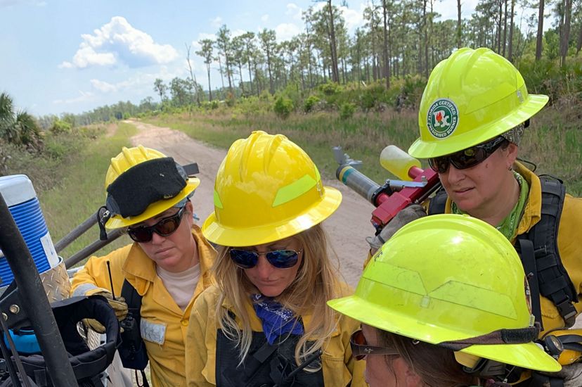Photo of four women in fire gear looking at a map for a controlled burn. 