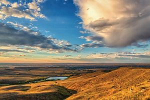 Landcape view of rolling hills at sunset with town in far background.