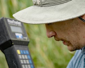 Close-up of a researcher's face in the foreground, and an out-of-focus scientific instrument in the background.