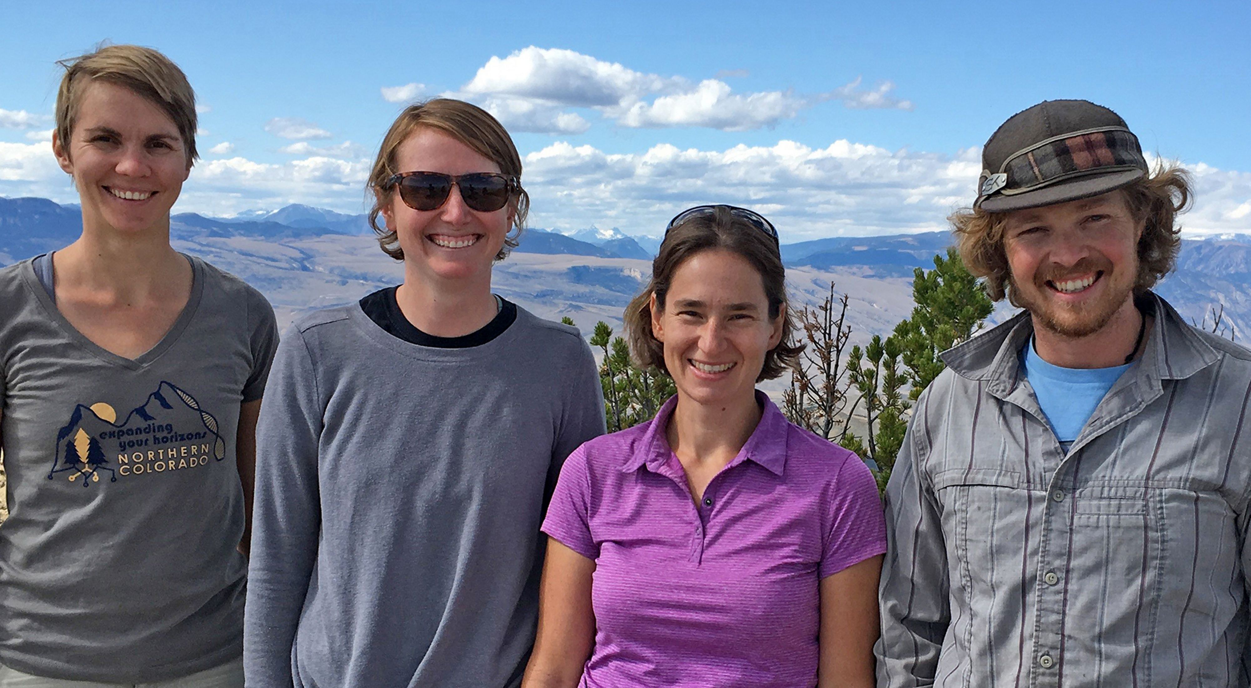 The Nature Conservancy in Wyoming science team--Dr. Courtney Larson, Maggie Eshleman, Dr. Corinna Riginos and Trevor Bloom--standing on a rocky ridge line, looking into the camera and smiling.