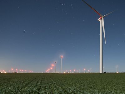 Lines of wind turbines in a green farm field.