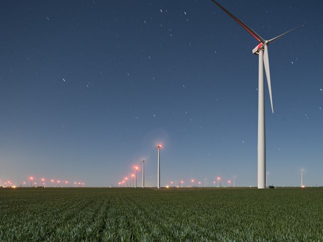 Lines of wind turbines in a green farm field.