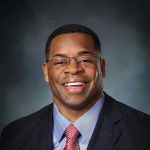 An African American man dressed in a business suit and smiling