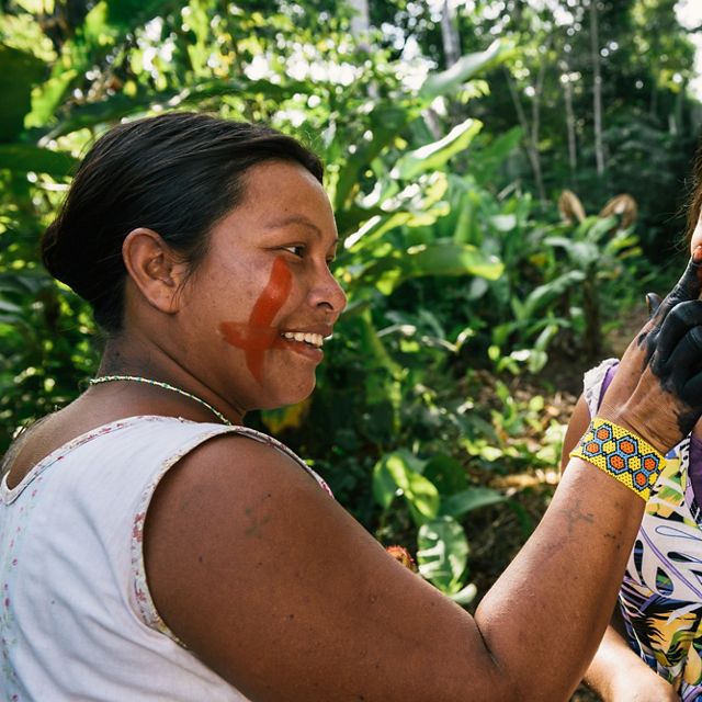 Xikrin women painting each other's faces in a forest near the Pot-Kro Village, Brazil.