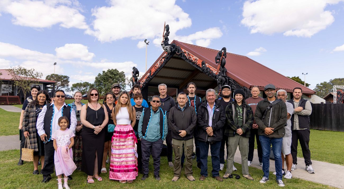 Several people gather together outside and pose for a photo.