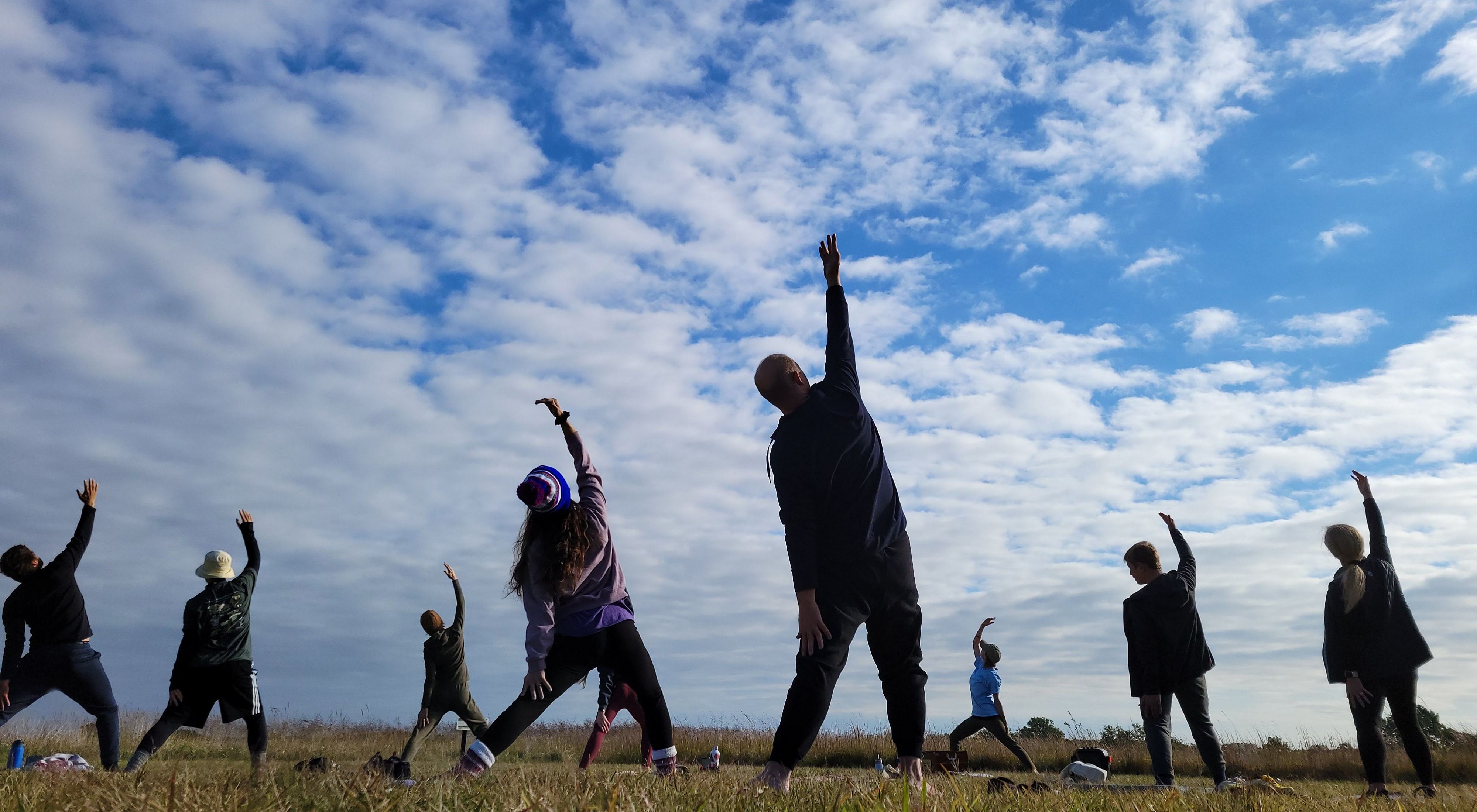 Group of people stretching their arms to blue skies during Yoga on the Prairie at Kankakee Sands.