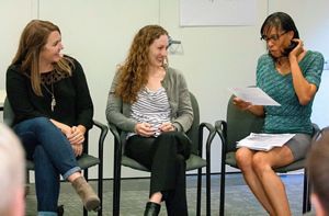 Three members of the Young Emerging Professionals group sit on chairs in a large room.