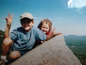 A grainy snapshot of two smiling kids posing at a mountain overlook.
