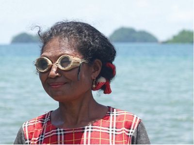 Marsince Korwa, a Waifuna Women's Group member, wears traditional diving goggles made of wood and glass.