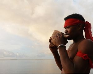 A young misool was blowing a trumpet from a triton shell.