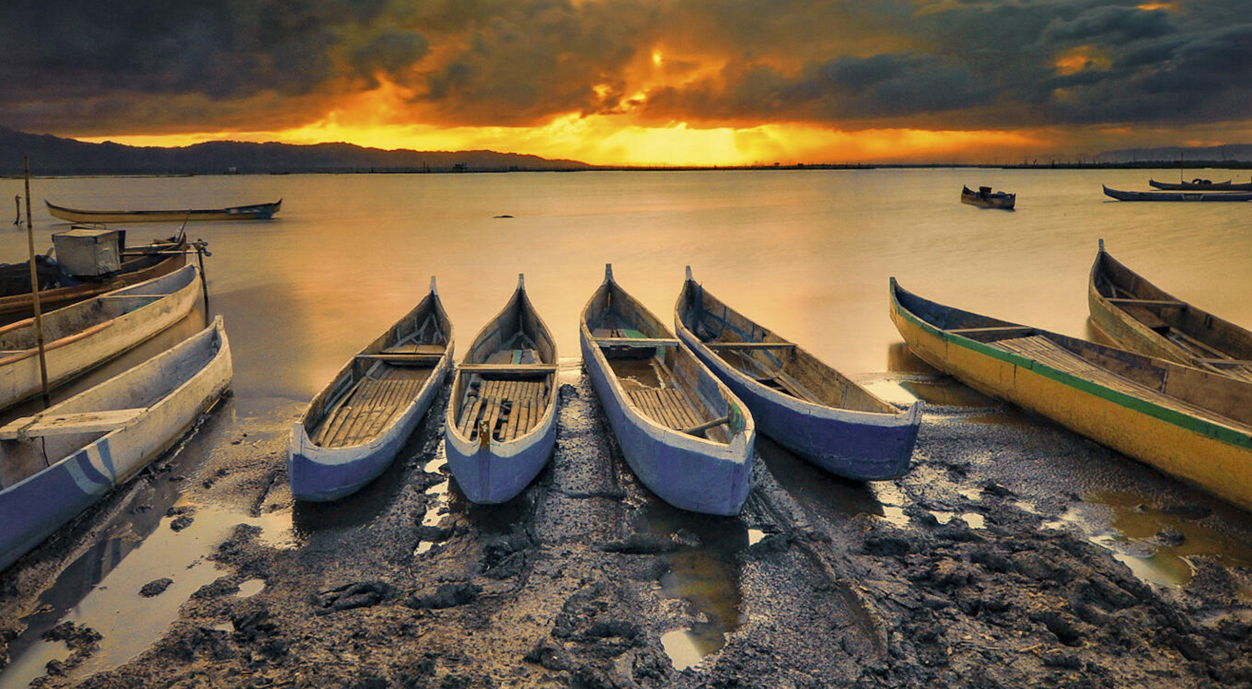 Sunset over a lake with canoes in the foreground.