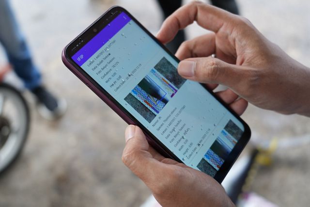 A hand holds a smartphone and looks at the FishFace app.