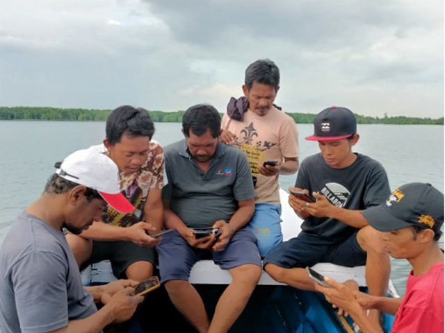 Beberapa nelayan di Bontang, Kalimantan Timur, sedang mencoba aplikasi e-logbook menggunakan smartphone di atas kapal.