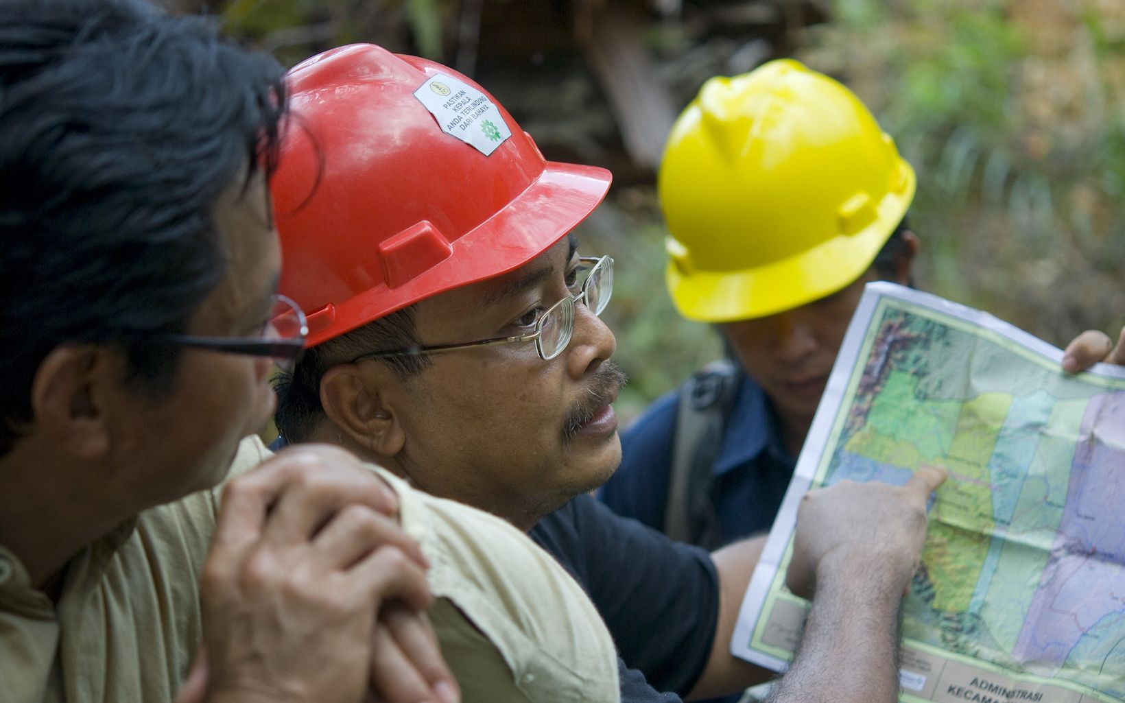 
                
                  Pemetaan Bambang Wahyudi (tengah) bekerja sama dengan perusahaan penebangan untuk mempraktekkan penebangan berdampak rendah (RIL).
                  © Bridget Besaw
                
              