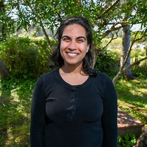 A person smiling in front of a forest.