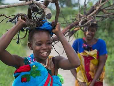Two young women carry firewood on their heads.
