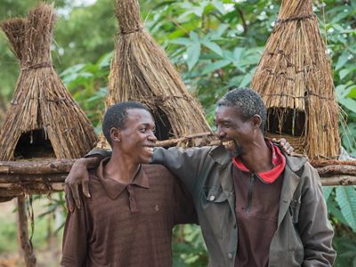A father and son stand in front of handmade chicken coops.