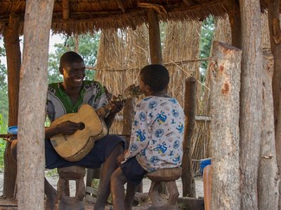 A man plays a handmade wooden guitar.
