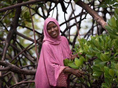 Zulfa Hassan, chair of Mtangawanda Women’s Association, smiles among mangroves.