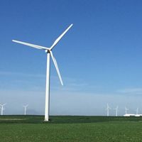 Photo of a wind turbine in a broad, flat Iowa field, with other turbines in background.