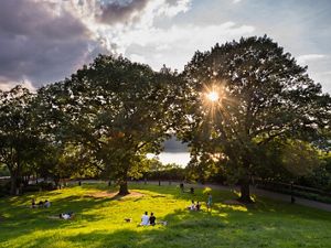 People enjoy the afternoon on the Billings Lawn of Fort Tryon Park along the Hudson River in Upper Manhattan, New York.